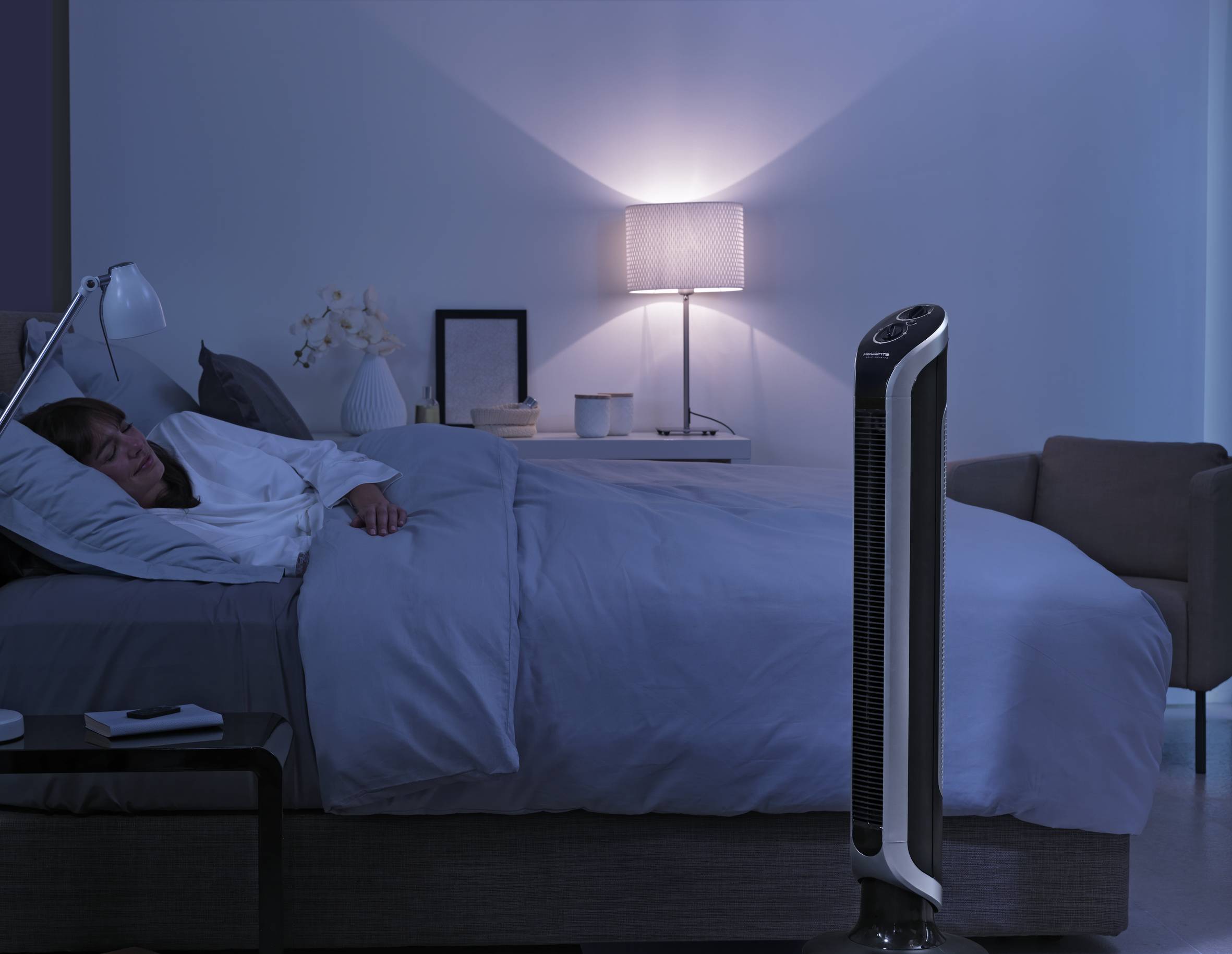 Frau schläft im Bett während Rowenta Standventilator kühlt